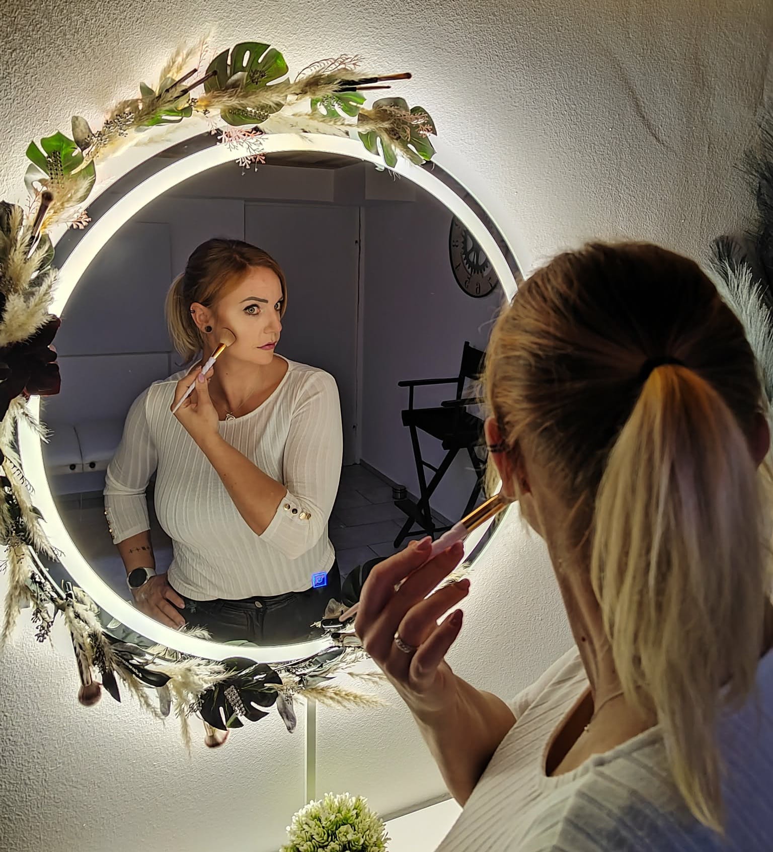 Profesionalno ličenje stranke pred osvetljenim ogledalom v salonu Balance & Beauty